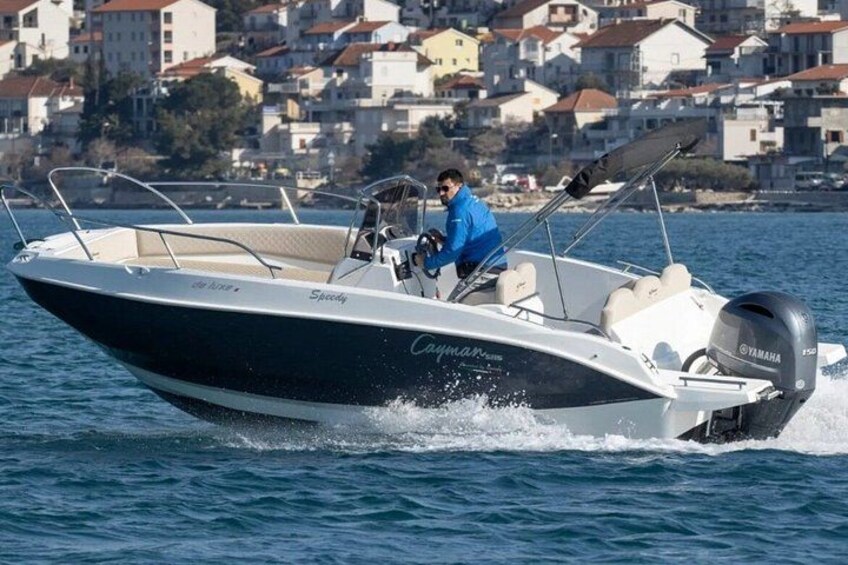 Un bateau à moteur filant sur l’eau, avec une personne à la barre, entouré d’une ville côtière. 2