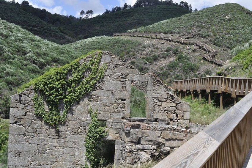 An ancient stone structure with ivy growth, wooden stairs, and a wooden bridge. 2