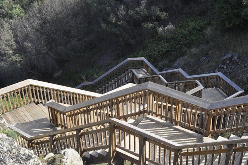 A wooden staircase with railings leading up a rocky hillside. 1