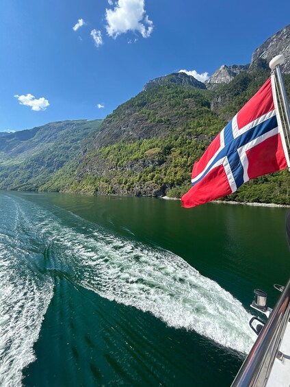 A boat on a lake with a Norwegian flag, mountains, and clear skies. 4