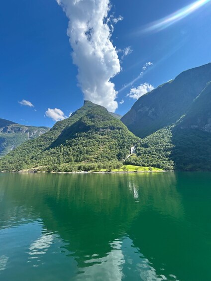 A mountain lake with a waterfall and lush greenery. 2