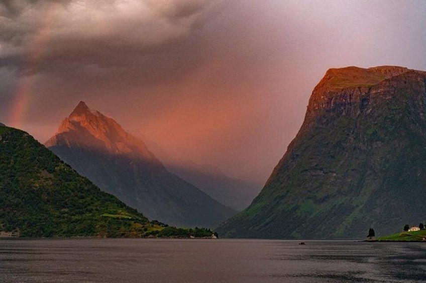 A mountain landscape with a rainbow, a lake, and a small building on the right. 2