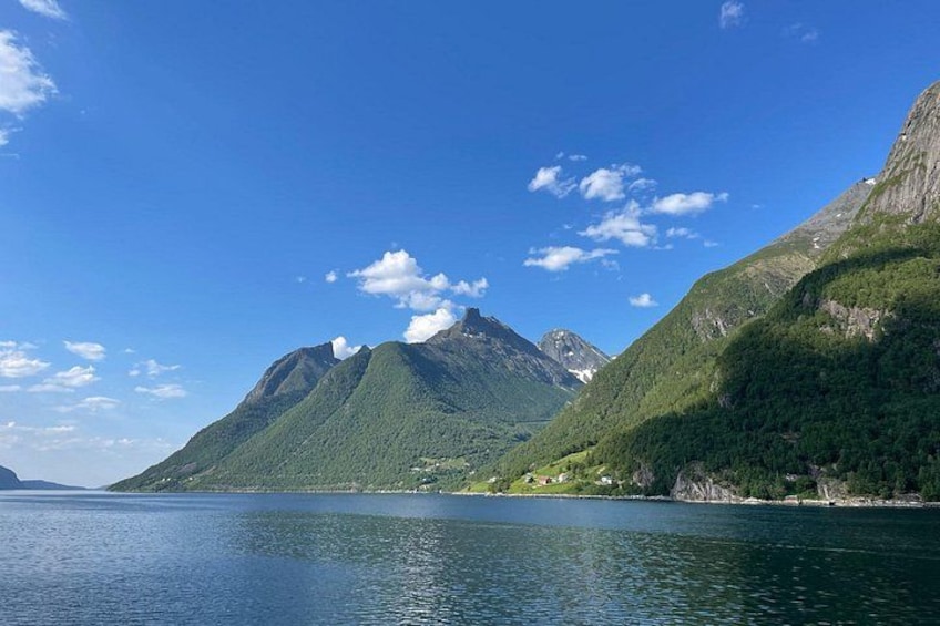 A calm lake surrounded by green mountains under a clear sky. 3