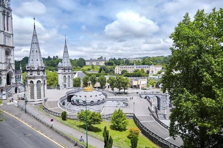 A historic city square with a circular building, a church, and a prominent tower. 4