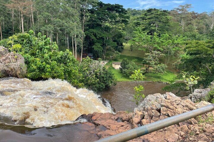 Un río con una cascada rocosa, abundante vegetación y un campo de golf al fondo. 5