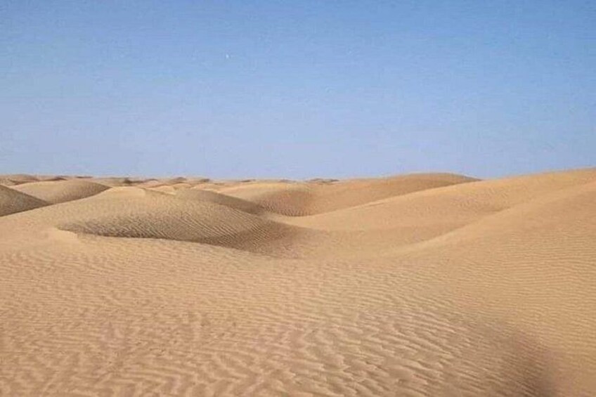 A desert landscape with sand dunes under a clear sky. 4