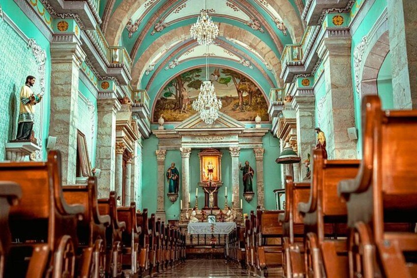 An ornate church interior with rows of pews, a central altar, and religious statues. 4