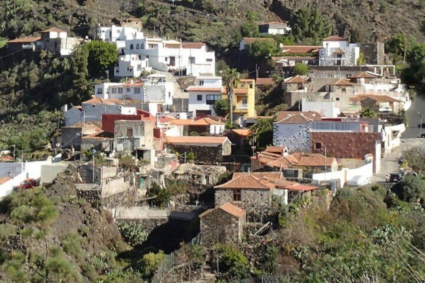 A hillside village with white and red-roofed buildings, surrounded by greenery and a river. 3