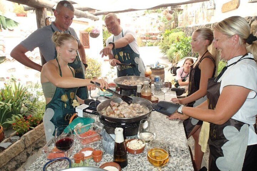 A group of people cooking outdoors with a grill, cooking utensils, and various food items on a table. 5