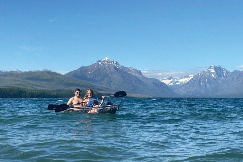Two people kayaking on a calm lake with mountains in the background. 3