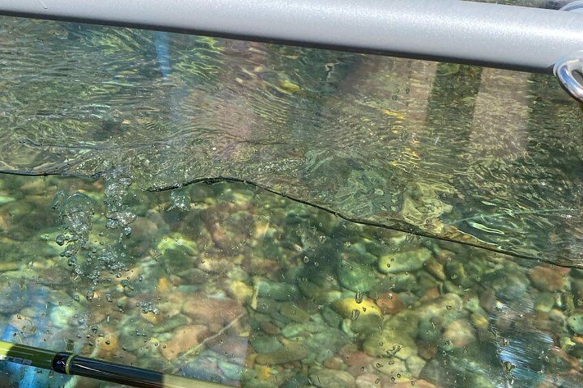 A clear glass surface with reflections of rocks and a metal bar. 2