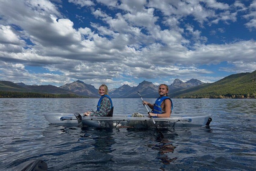 Two people in a canoe on a lake with mountains in the background. 1