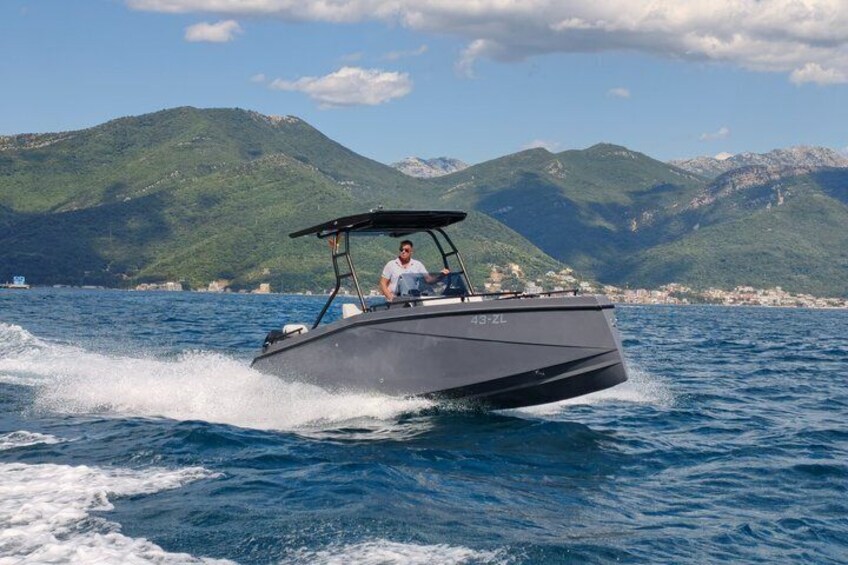 Ein Schnellboot auf dem Wasser, im Hintergrund Berge. 1