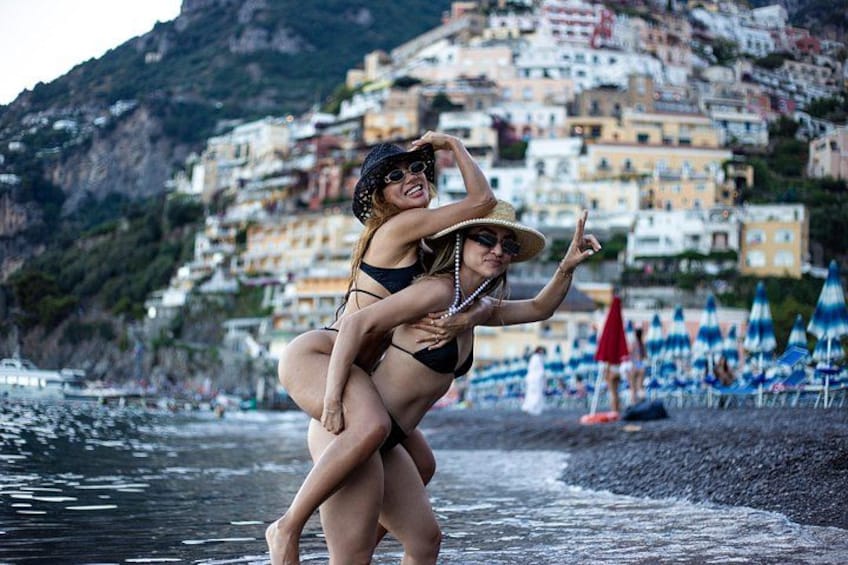 A beach with people, a woman in a bikini, and colorful buildings in the background. 5