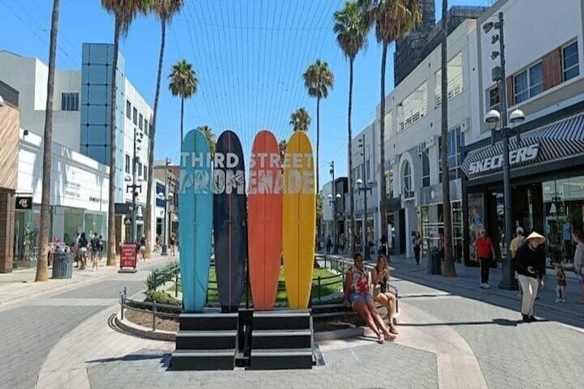A street with surfboards, palm trees, and storefronts. 3