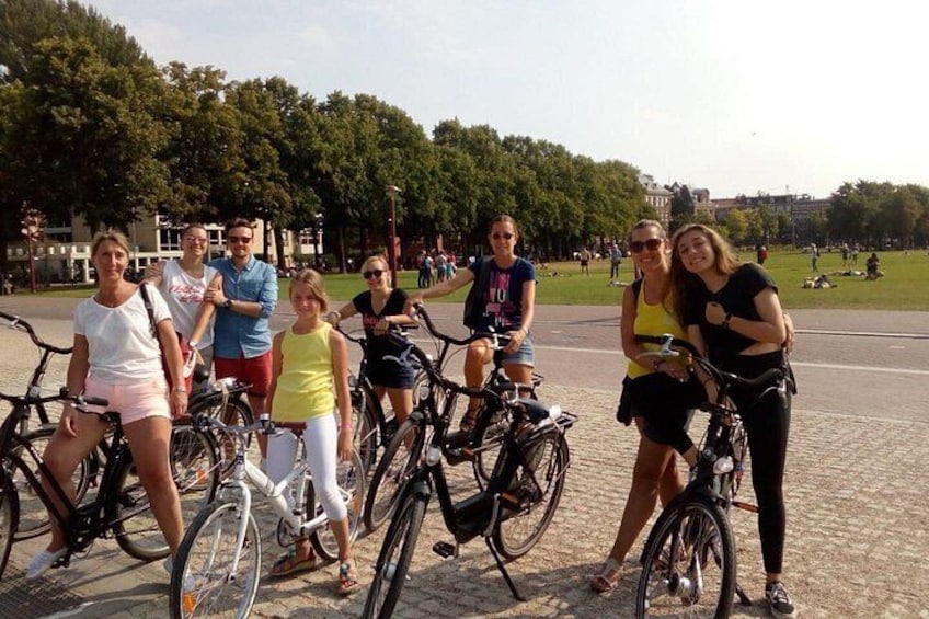 Un grupo de personas con bicicletas en un parque con árboles y un camino pavimentado. 2