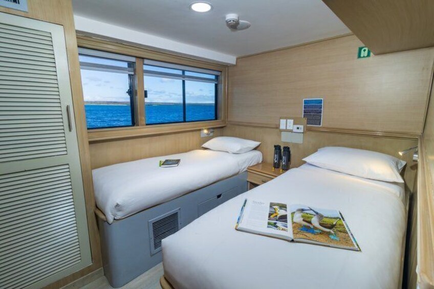 A cabin with two beds, a window, and a view of the sea. 5
