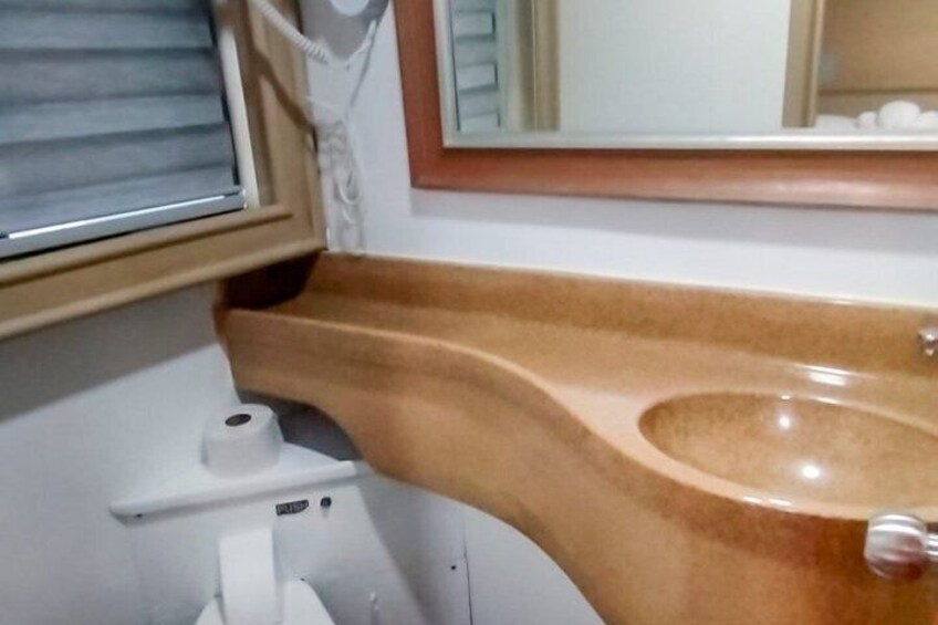 A bathroom with a wooden vanity, a sink, a toilet, and a mirror. 2