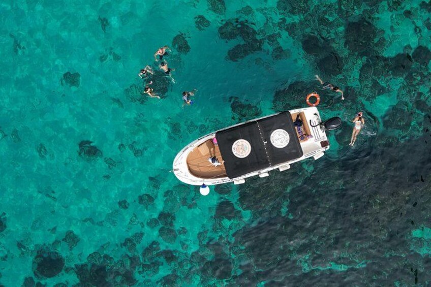 Ein Boot, um das Menschen in klarem, türkisblauem Wasser schwimmen. 5