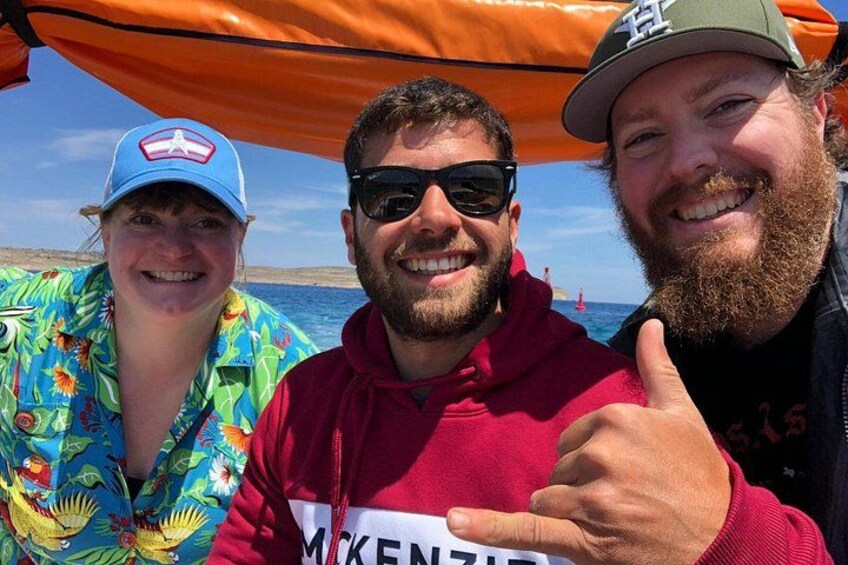Drei Personen unter einer orangefarbenen Markise am Meer. 1