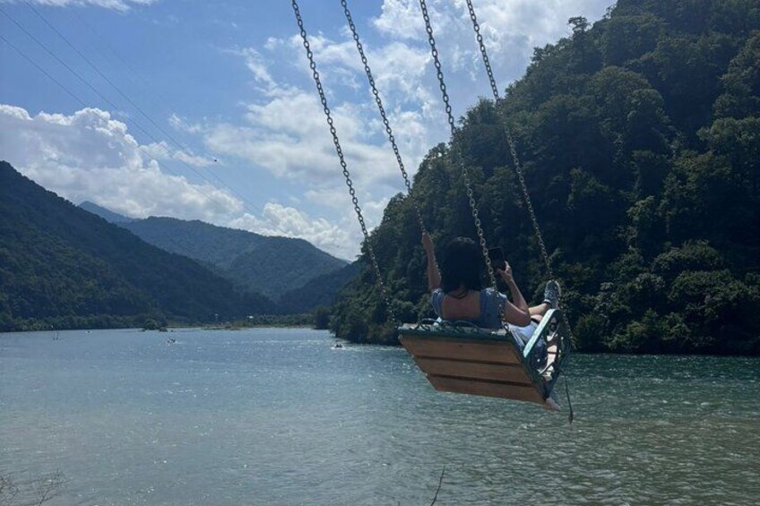 A wooden swing boat on a calm lake surrounded by mountains. 5