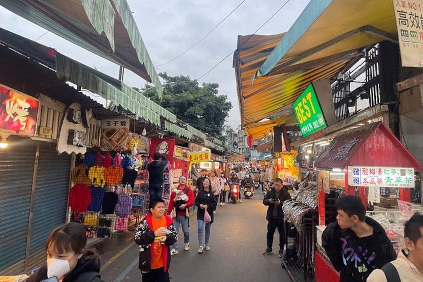 A bustling street market with various stalls and shops. 2