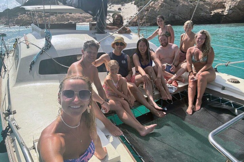 A group of people on a boat with rocky cliffs and clear blue water in the background. 3