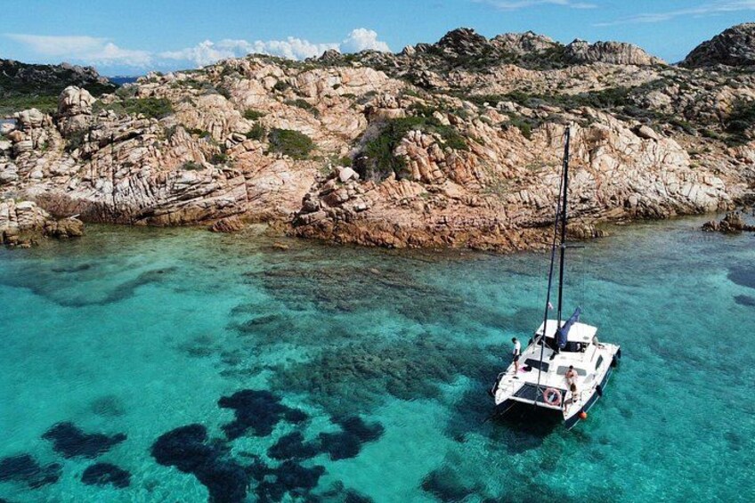 Een zeilboot ankerde nabij rotsachtig terrein met helder turquoise water. 2