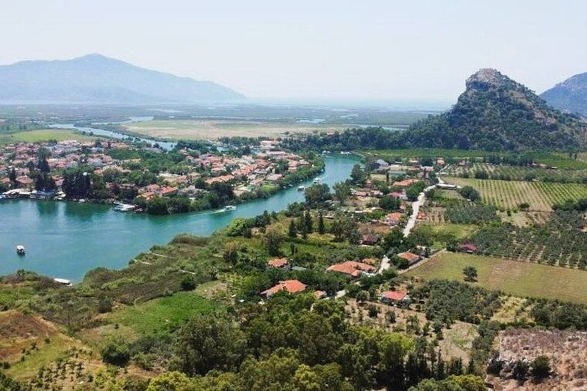 A river winding through a town with red-roofed houses, surrounded by green fields and hills. 5