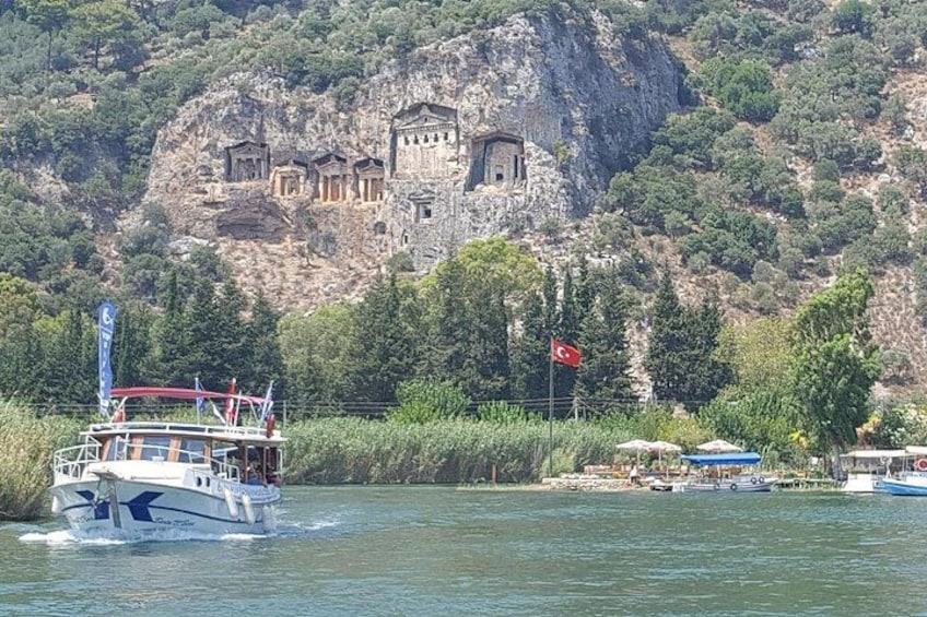 A boat on a river with a rocky cliff and ancient ruins in the background. 1