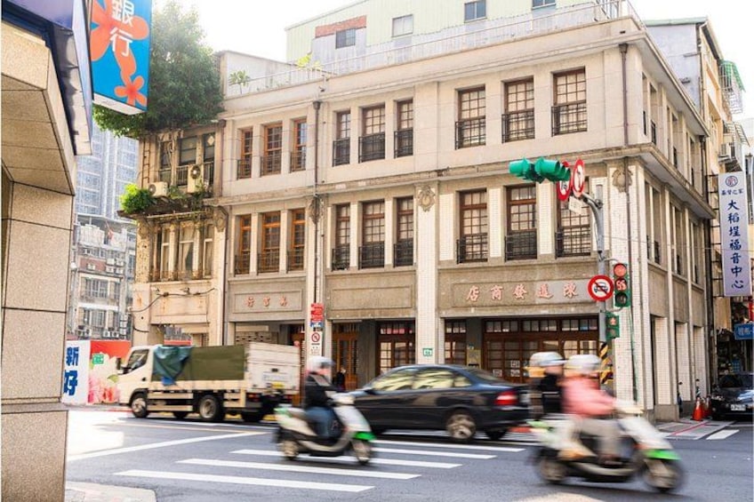 A street with a building, traffic signs, and vehicles. 1