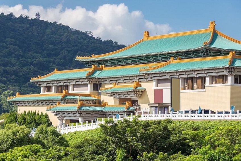 A traditional multi-tiered building with green roofs and white walls, surrounded by lush greenery and hills. 2