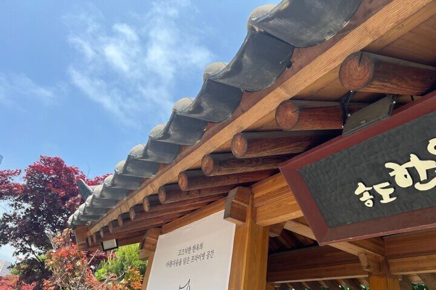 A traditional Korean roof with wooden beams and a signboard. 3