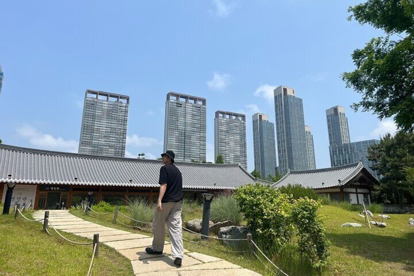 A person walking on a path in a park with traditional buildings and modern skyscrapers in the background. 4