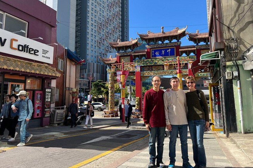 A street with a coffee shop, a traditional gate, and pedestrians. 4