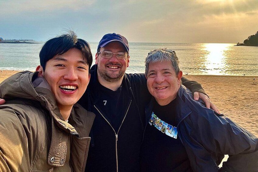Three people on a beach with the ocean and a pier in the background. 5