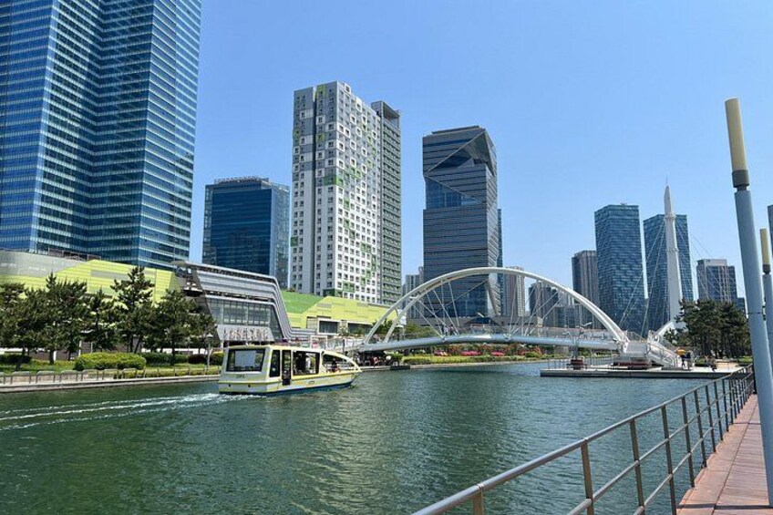 A river with a boat, a modern bridge, and high-rise buildings in the background. 3