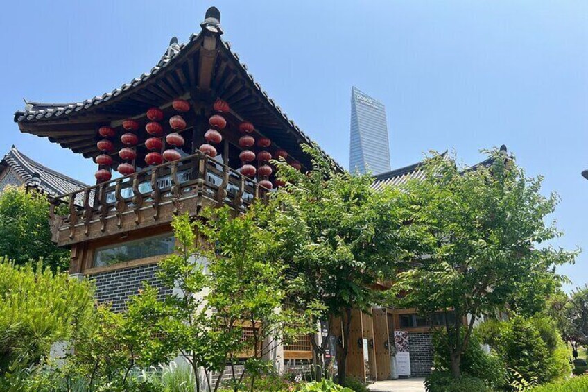 A traditional building with a tiled roof and red lanterns, surrounded by greenery and modern skyscrapers in the background. 5