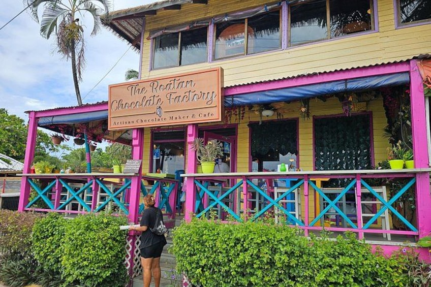 Ein farbenfrohes Gebäude mit einem Schild, auf dem 'The Roatan Chocolate Factory' steht. 4