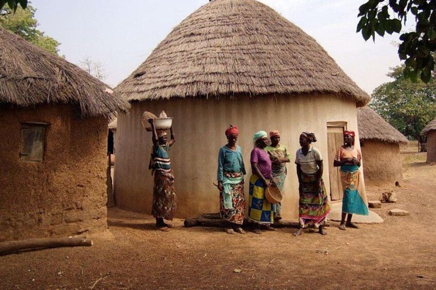 A rural village with thatched-roof huts, women in colorful traditional attire, and a dirt ground. 3