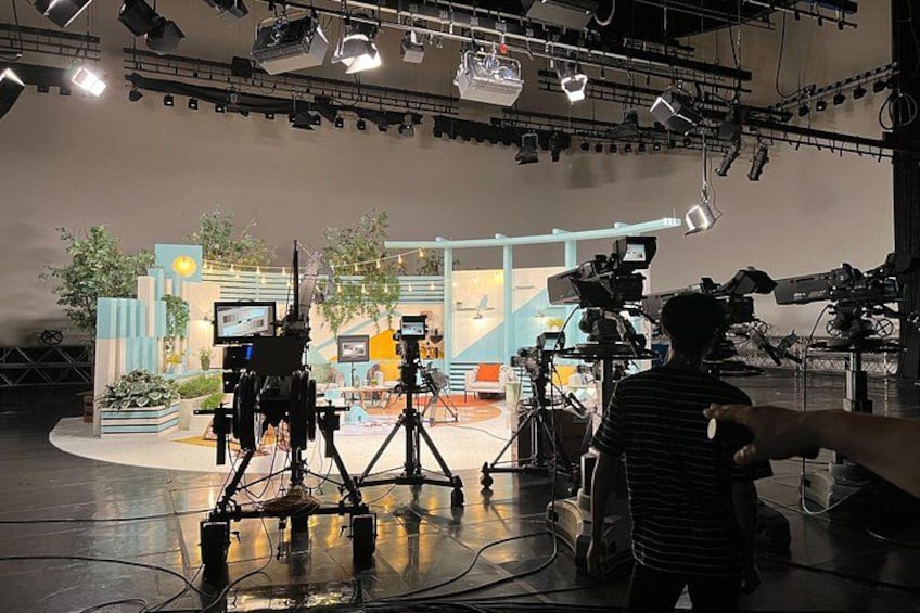 A film set with cameras, lighting equipment, and a person in a striped shirt. 4