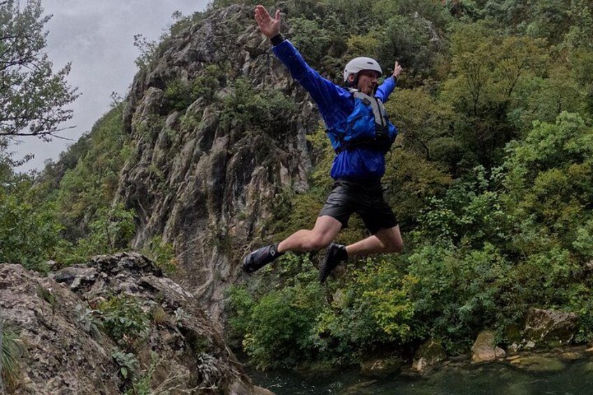 Une personne qui saute d’une falaise dans une rivière, entourée d’une forêt dense. 4
