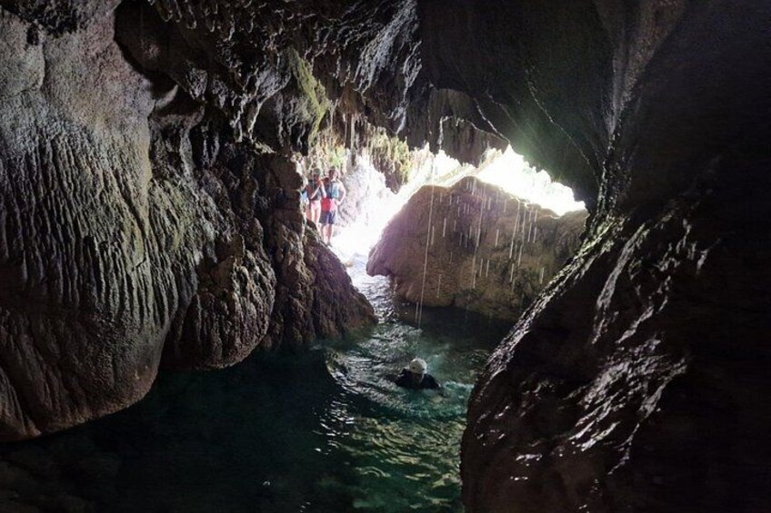 Una cueva con agua que fluye, paredes rocosas y una persona nadando. 4