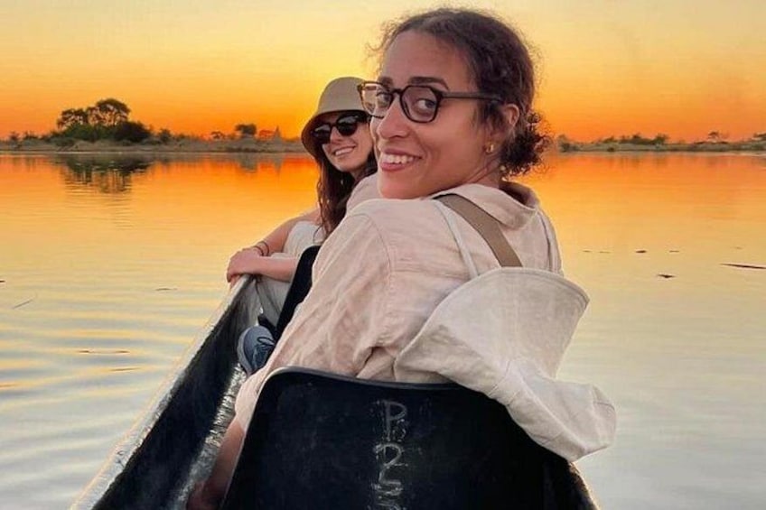 Two people in a boat on a calm body of water during sunset. 1