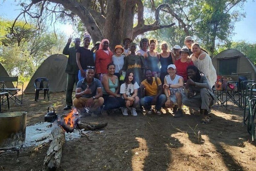 A group of people camping outdoors with tents and a campfire. 5