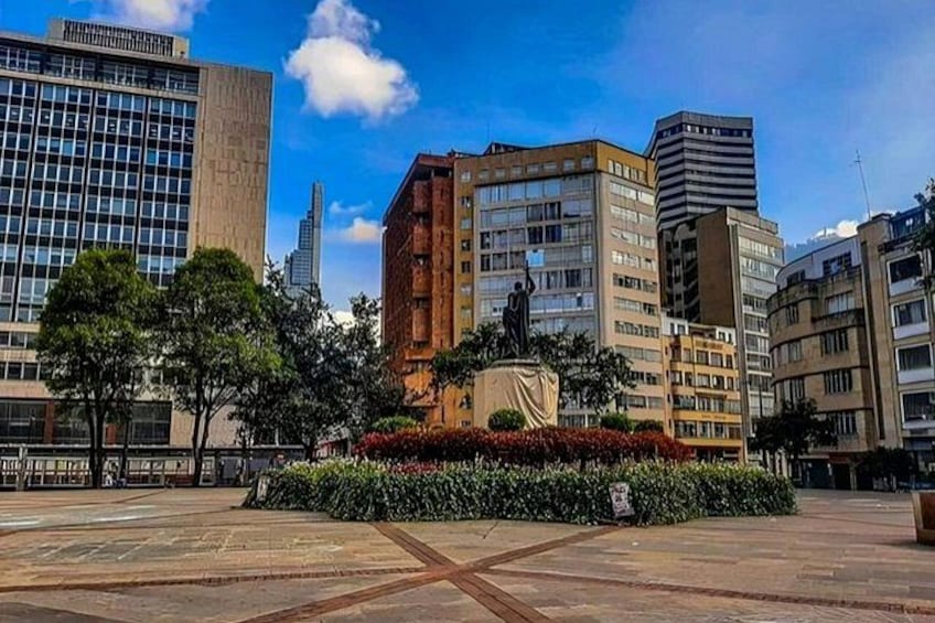 A city square with a statue, modern buildings, and a clear sky. 5