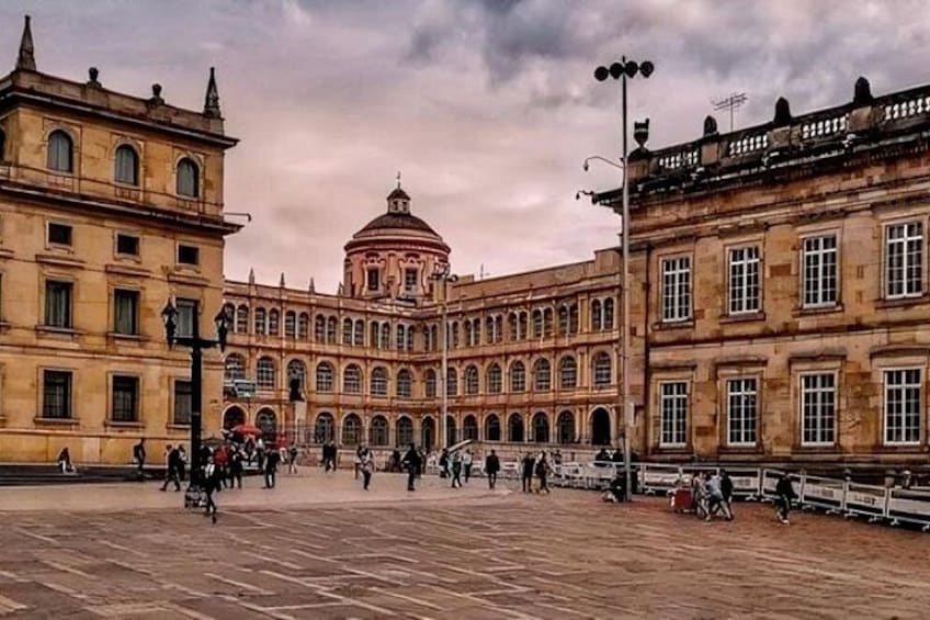 A historic plaza with classical architecture, including a prominent building with a dome and arched windows. 4