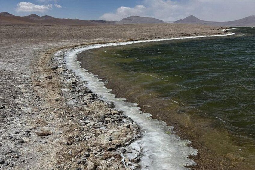 Un río con una orilla rocosa y montañas a lo lejos. 5