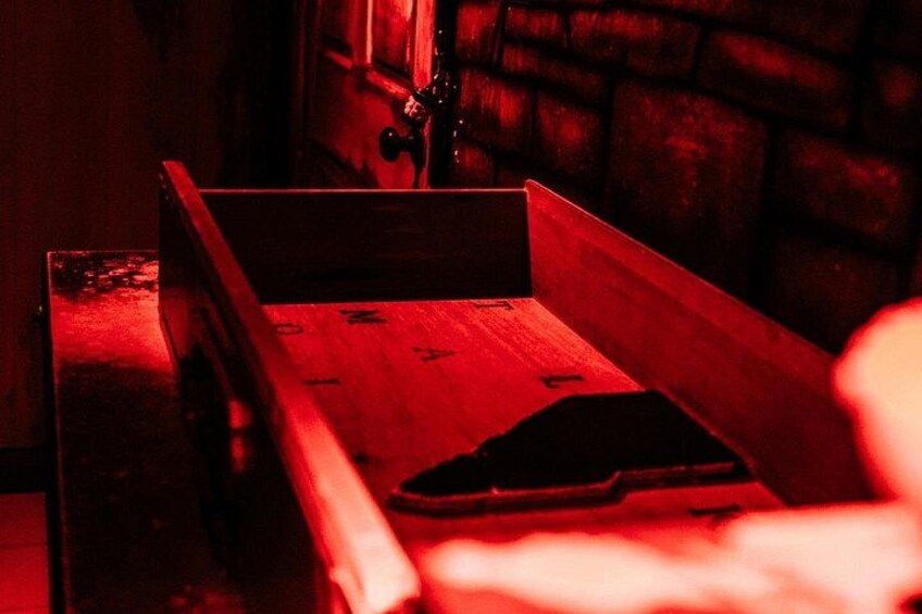 Un banc en bois avec une structure métallique, une source de lumière rouge et un mur de pierre en arrière-plan. 2