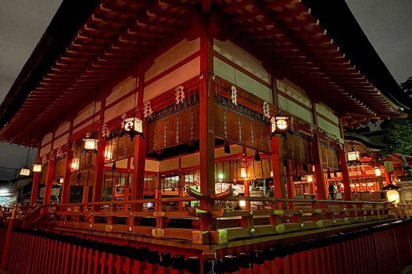 Ein traditionelles japanisches Gebäude mit roten und weißen Wänden, hölzernen Balken und hängenden Laternen. 4